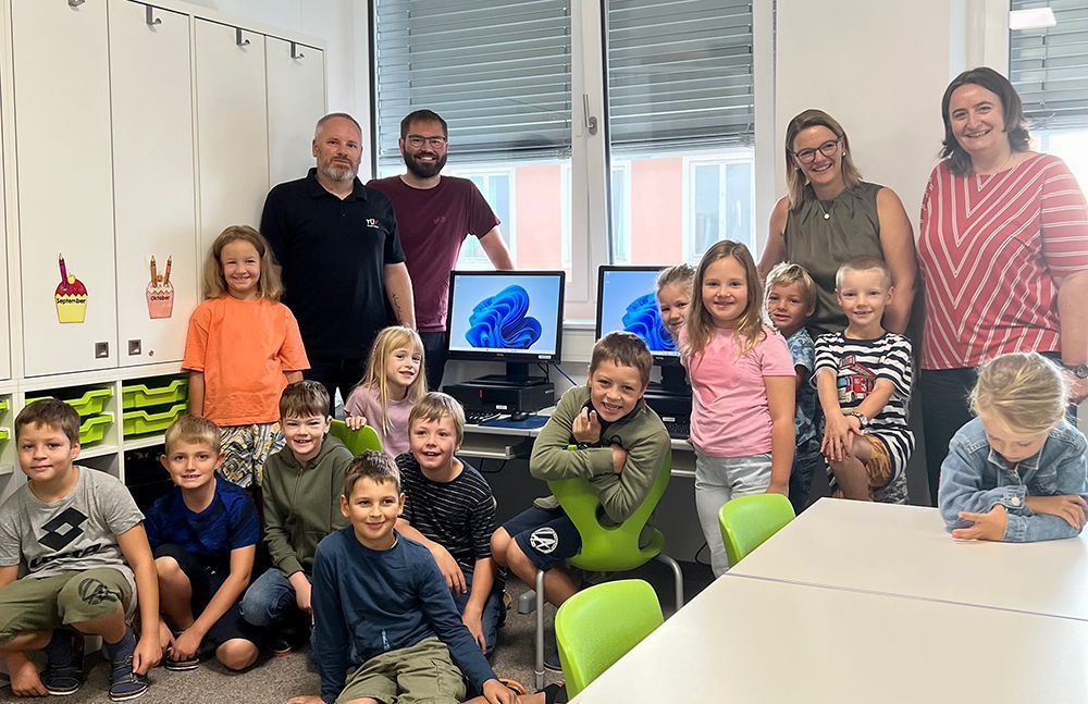 Bernd Viehböck (TÜV AUSTRIA) und August Wurm (ReWir Coworkingspace) mit Michaela Angster (Direktorin), Ursula Höllinger-Dannerer (Lehrerin 2B), und Schüler_innen der 2B der Volksschule Hartkirchen bei der Spendenübergabe. | (C) ReWir Coworking Space, August Wurm / Volksschule Hartkirchen 